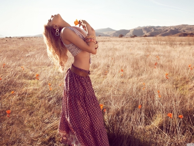 Девушка с маком стоит посреди поля