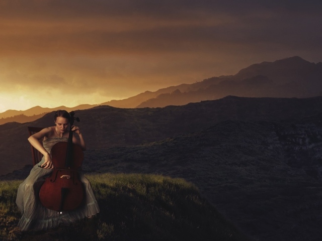 Девушка играет на виолончели на фоне гор