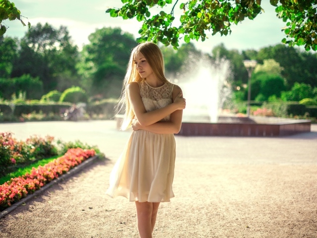 Блондинка в парке на фоне фонтана
