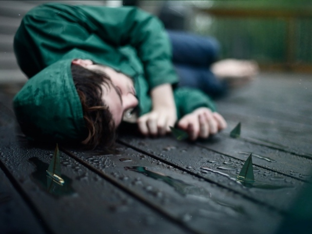 Девушка в зеленом лежит на мокрых досках