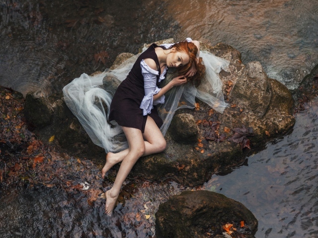 Девушка лежит на камне среди воды