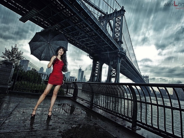 Модель в красном платье с зонтом стоит под мостом