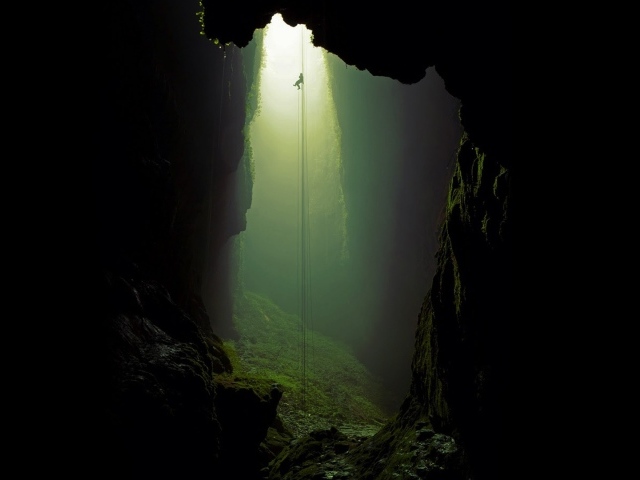 Спелеолог спускается по канату в пещеру