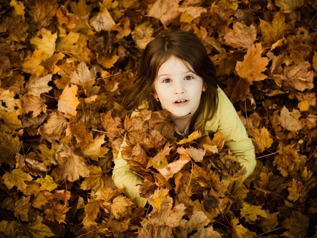 Девочка зарылась в опавшие листья