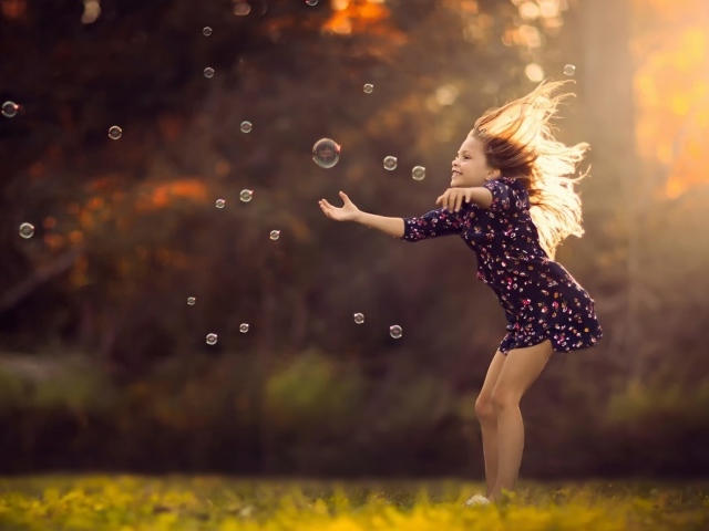 Девочка играет с мыльными пузырями