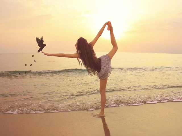 Балерина на берегу моря с птицей