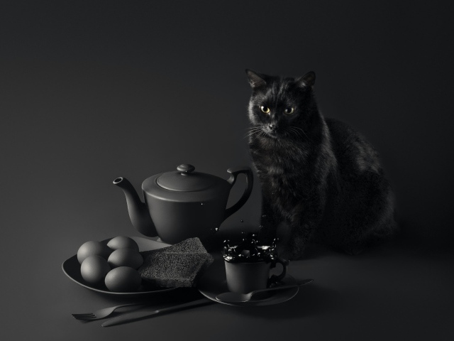 Черный кот сидит на столе с завтраком