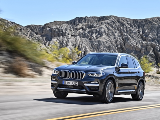 Черный красивый автомобиль BMW X3, 2018 на фоне гор