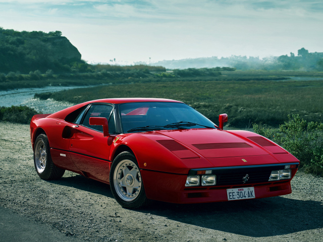 Красный быстрый автомобиль Ferrari 288 GTO у реки