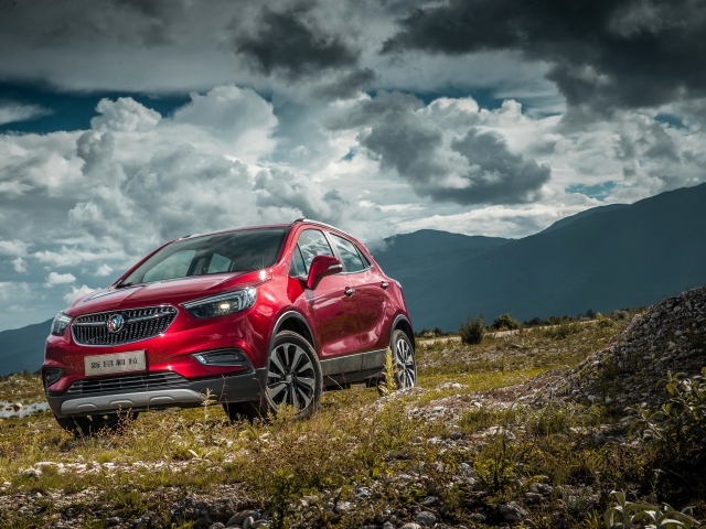 Красный автомобиль Opel Mokka на фоне облачного неба 