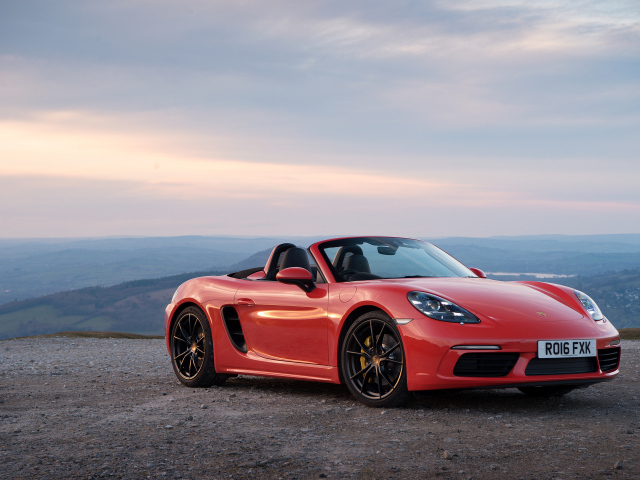 Красный автомобиль кабриолет Porsche 718 Boxster на фоне горизонта 