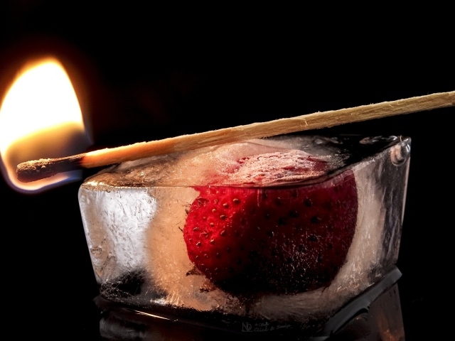 Зажженная спичка на кусочке льда с клубникой 