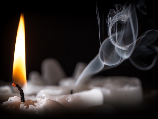 Огонь горящей свечи с дымом на черном фоне