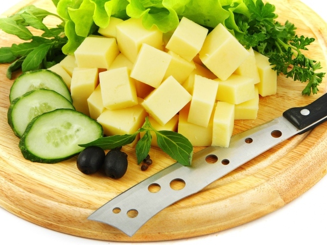 Сыр нарезанный кубиками на разделочной доске