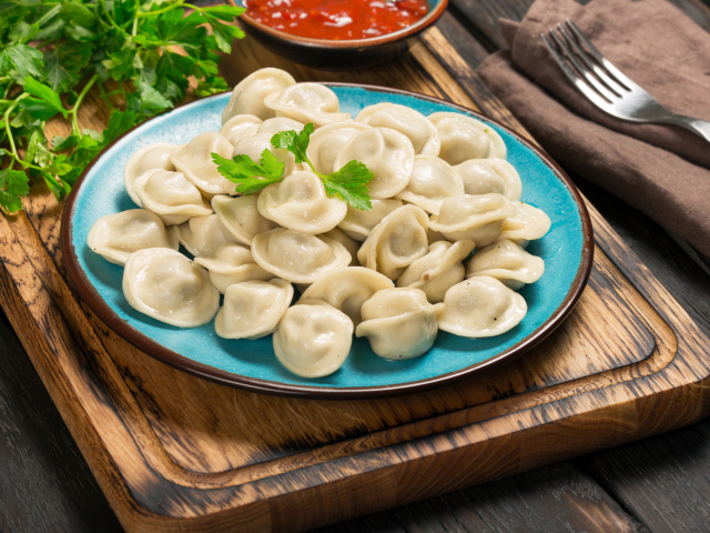 Вкусные пельмени на голубой тарелке 