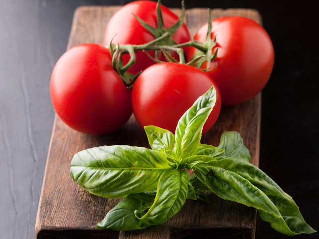 Свежие помидоры на разделочной с зеленью