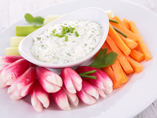 Свежие овощи с соусом в белой тарелке 