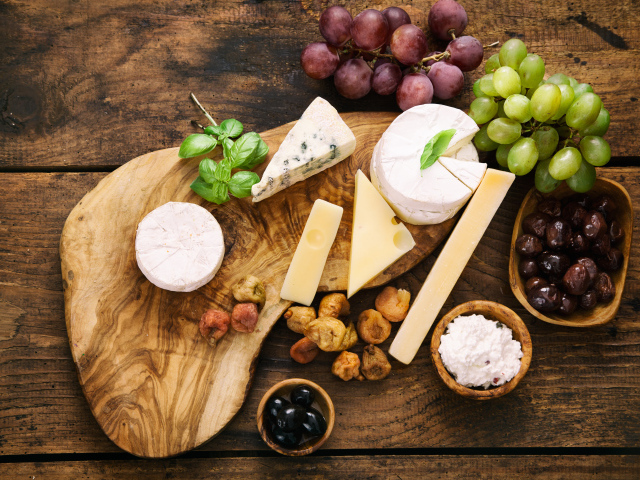 Кусочки сыра с виноградом и оливками на столе