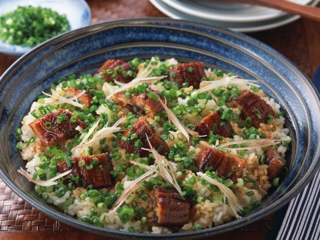 Рисовый плов с кусочками мяса и зеленым луком на столе