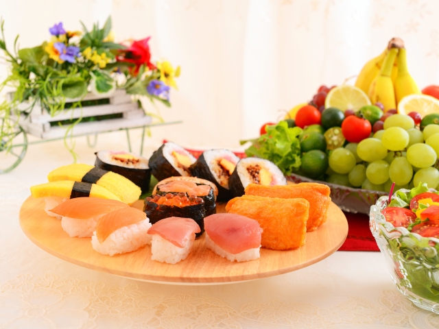Суши на столе с фруктами и салатом из овощей