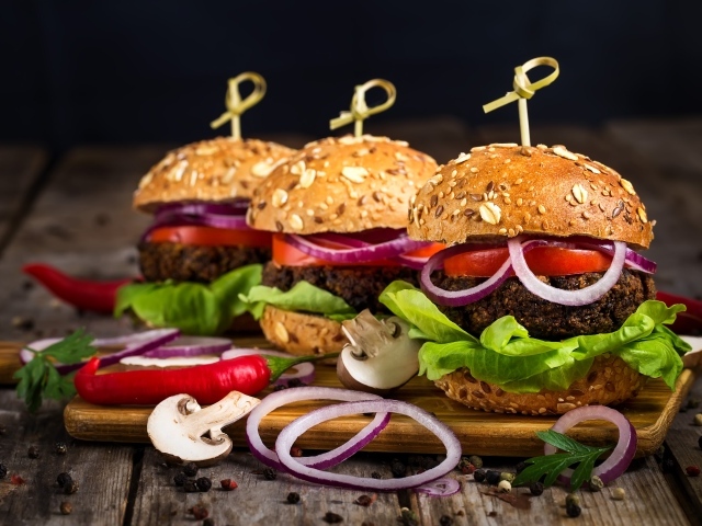 Три аппетитных гамбургера с кольцами лука и перцем