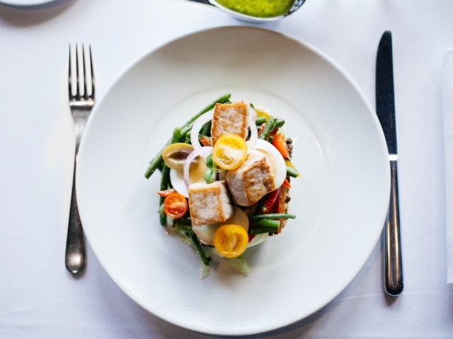 Овощной салат на белой тарелке со столовыми приборами