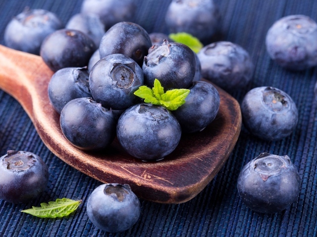 Ягоды спелой черники на деревянной ложке крупным планом