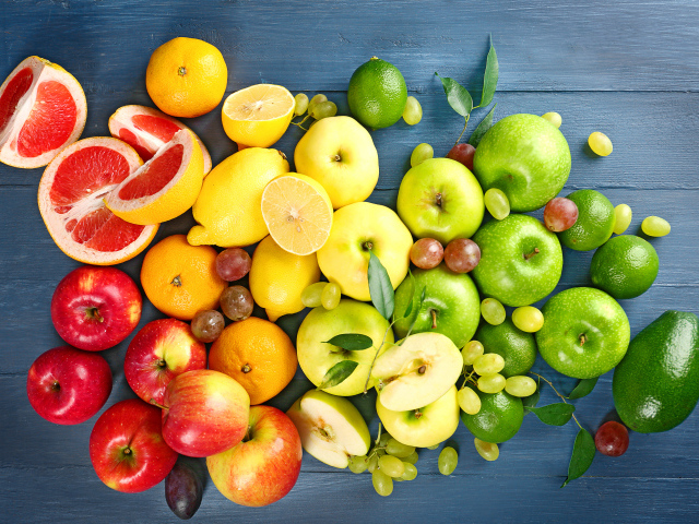 Свежие яблоки, авокадо, лимоны, мандарины и  виноград на столе