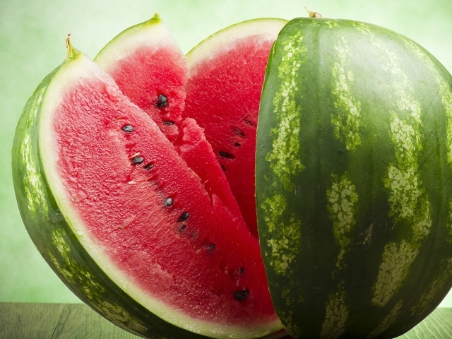 Большой спелый арбуз нарезанный скибками  на столе