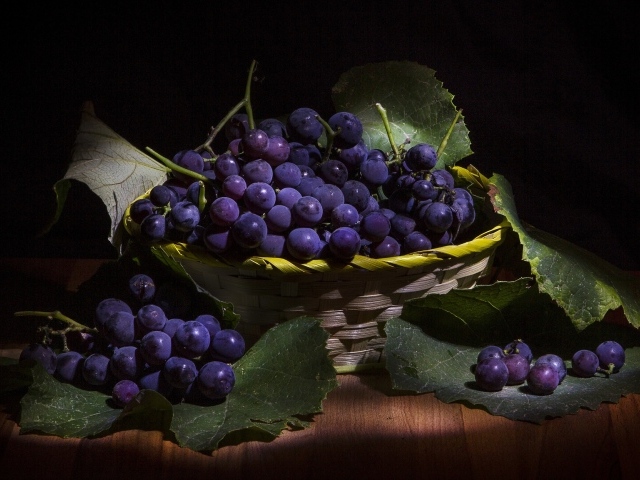 Круглый синий виноград в корзине на столе