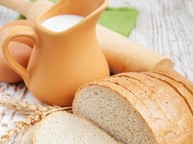 Белый нарезанный батон на столе с молоком