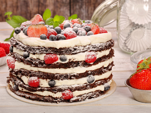 Аппетитный торт с кремом и ягодами посыпан сахарной пудрой