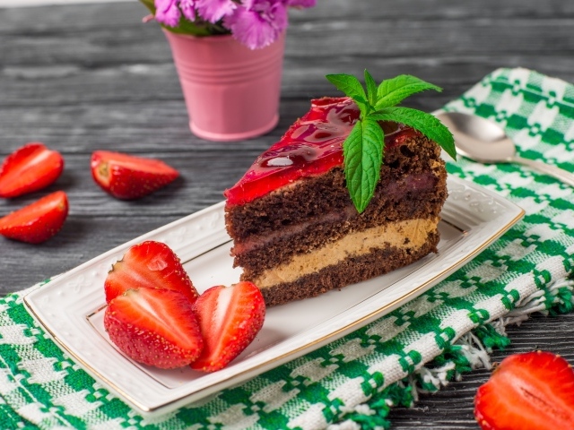 Аппетитный кусок торта на тарелке с ягодами клубники