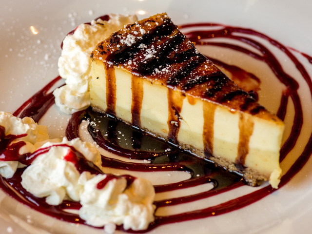 Аппетитный кусок чизкейка со сливками и клубничным джемом