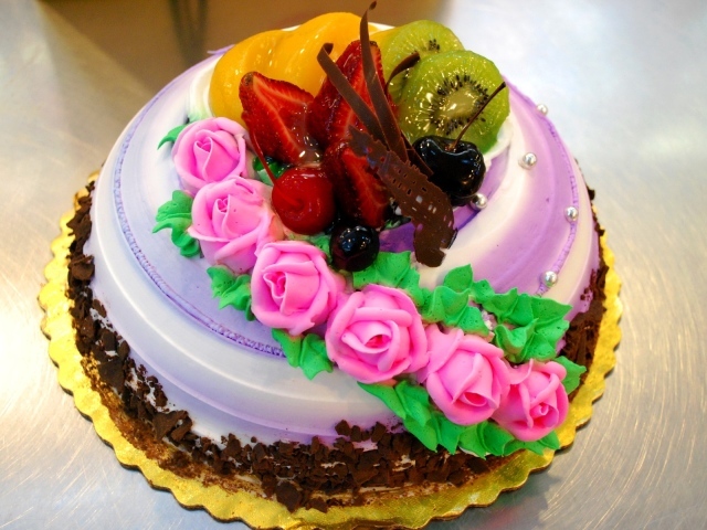 Красивый торт с фруктами украшен розовыми розами из крема