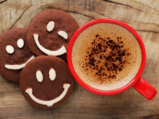 Шоколадное печенье смайлы на столе с чашкой кофе