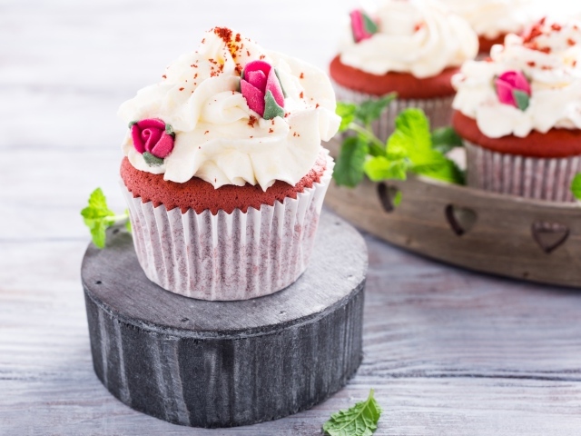 Шоколадный капкейк с кремом и розочками на столе