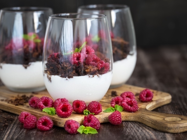 Десерт со сливками, шоколадом и свежей малиной в стеклянных стаканах