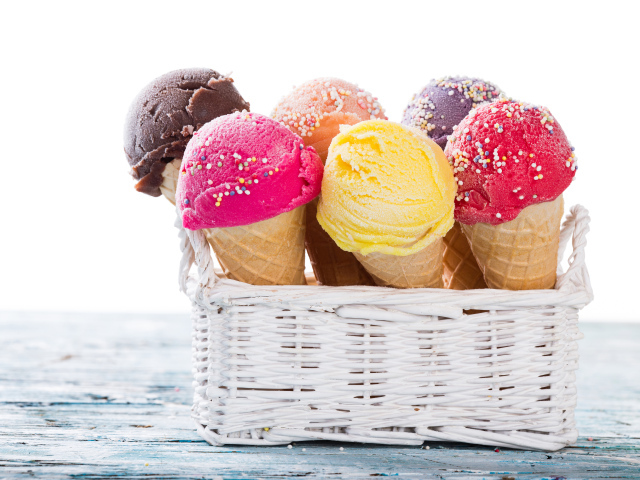 Разноцветное мороженое в вафельных рожках в белой корзине на столе