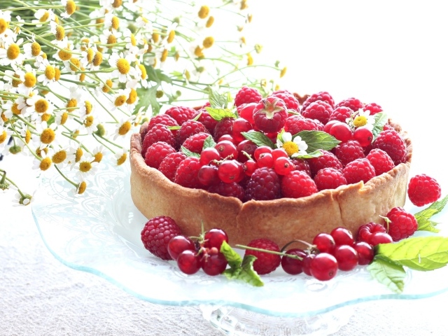 Пирог с ягодами малины и смородины на столе с ромашками
