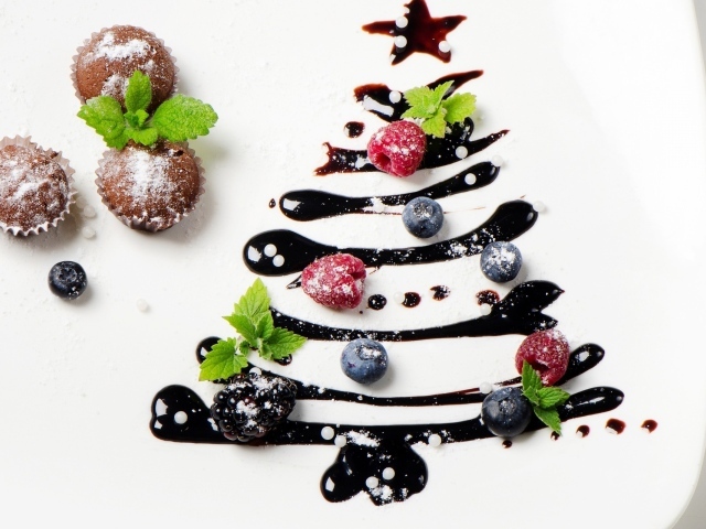 Три кекса и нарисованная шоколадом елка на белой тарелке