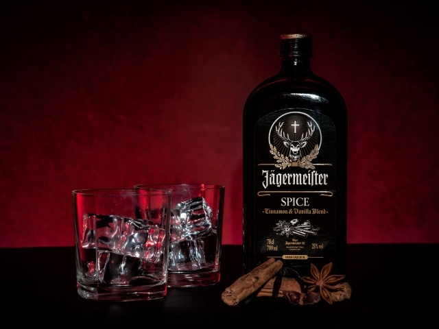 Бутылка ликера Jägermeister на столе с корицей и стаканами