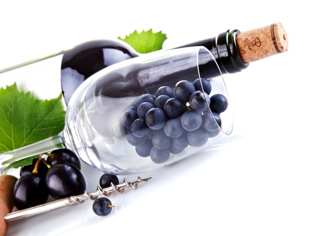 Бутылка вина с бокалом и виноградом на белом фоне