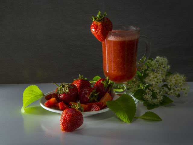 Стакан клубничного сока и свежая клубника на столе