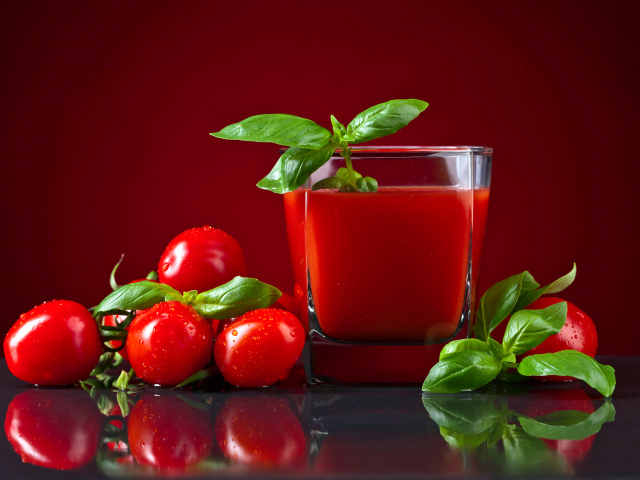 Стакан томатного сока со свежими помидорами на столе