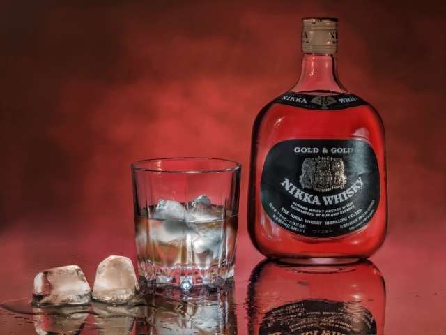 Бутылка Nikka Whisky на столе со стаканом со льдом