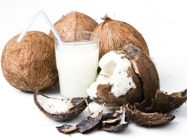 Кокосовое молоко в стакане и кокосы на белом фоне