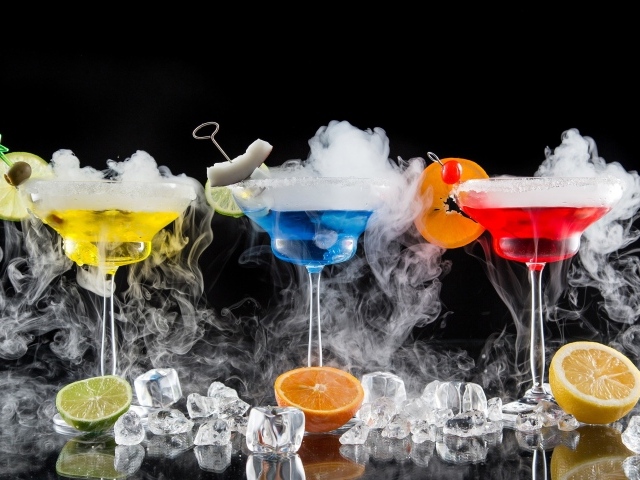 Три алкогольных коктейля с сухим льдом на черном фоне