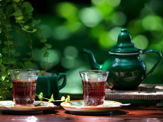 Две чашки чая и зеленый чайник на столе 