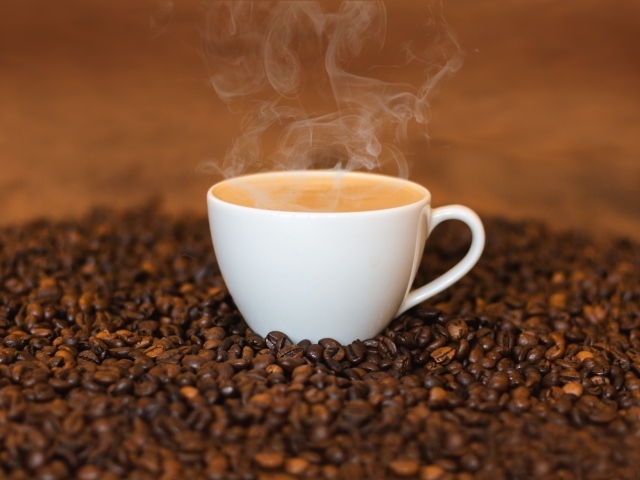 Белая чашка с кофе на кофейных зернах